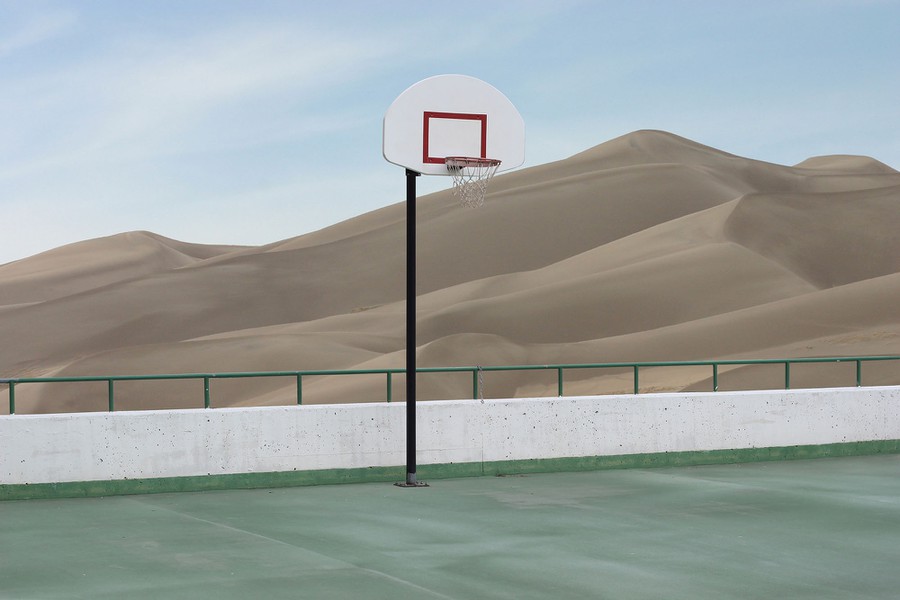 A basketball court amidst desert sand dunes.